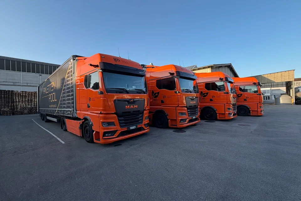 Vier orange Lastwagen der Paletten-Pool GmbH auf dem Werkhof in Oberbipp; die drei hinteren tragen das Elektro-Signet